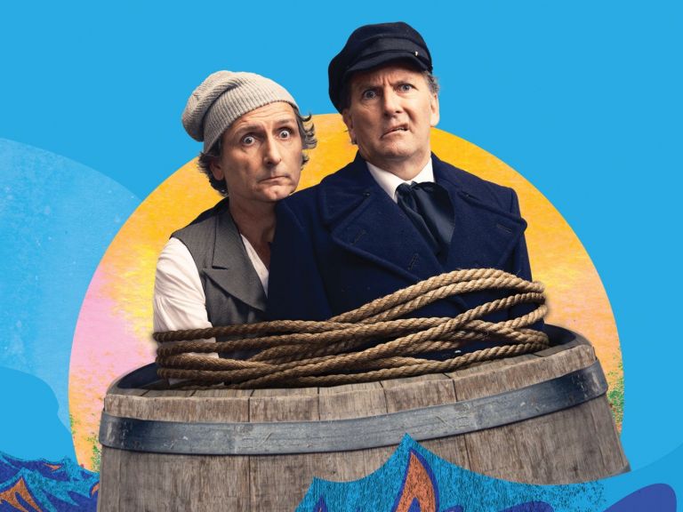 Lano & Woodley sit in a barrel in front of a blue background.