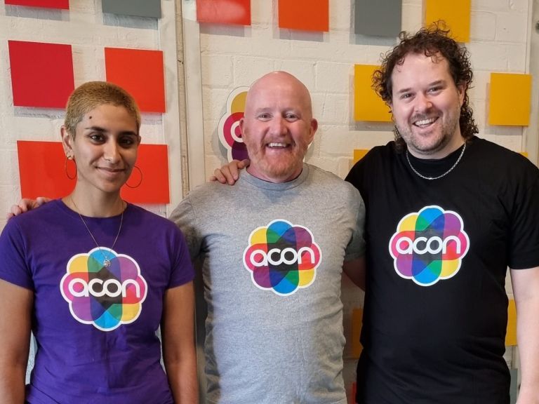 three people with t-shirts that say 'ACON'
