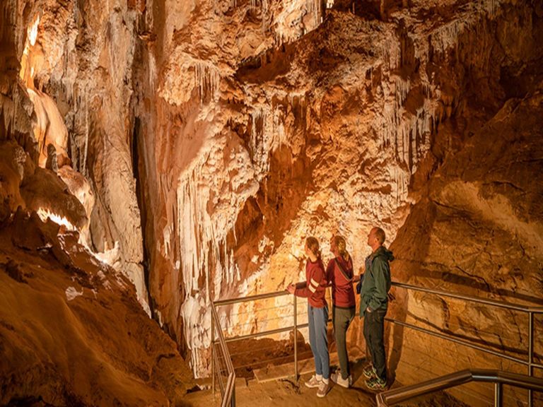 3 people standing in the Fig Tree Cave looking at geological features at Wombeyan Karst Conservation
