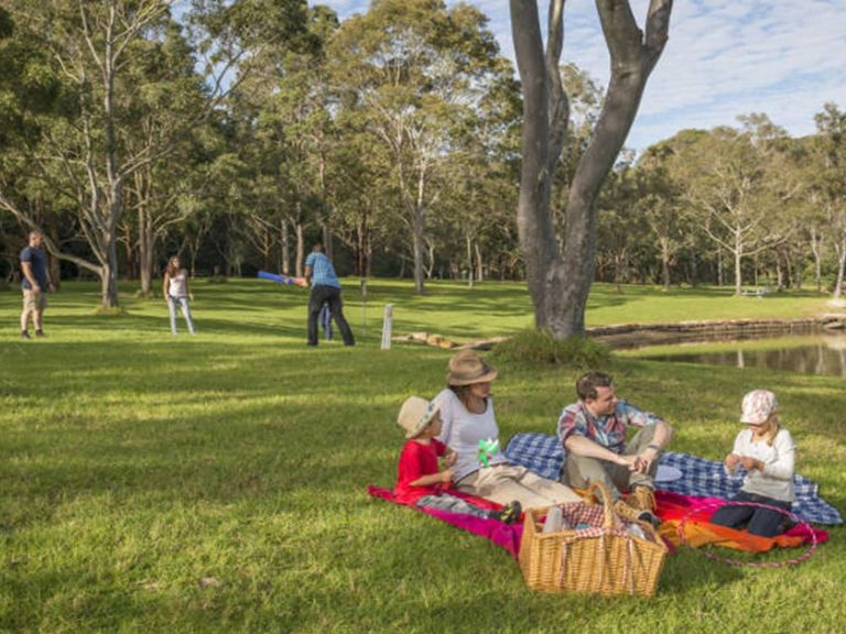 Family enjoying a picnic on the grass at Davidson Park picnic area in Garigal National Park. Photo: