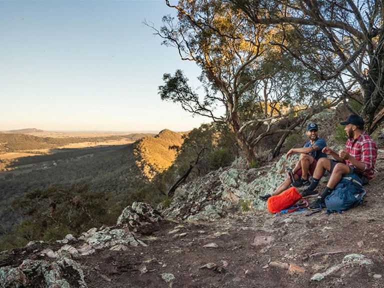 Two men sit on the ground at a viewpoint in The Rock Nature Reserve - Kengal Aboriginal Place.