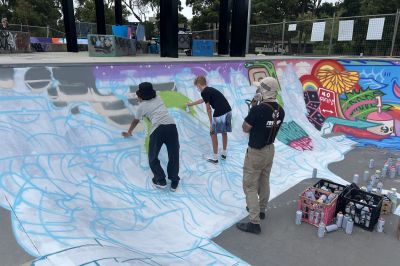 Sam Absurd creating mural at local skate park alongside young people