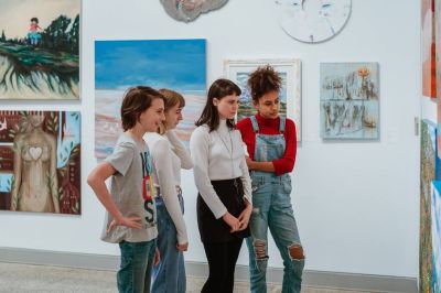 A group of teenagers looking at an artwork on a wall