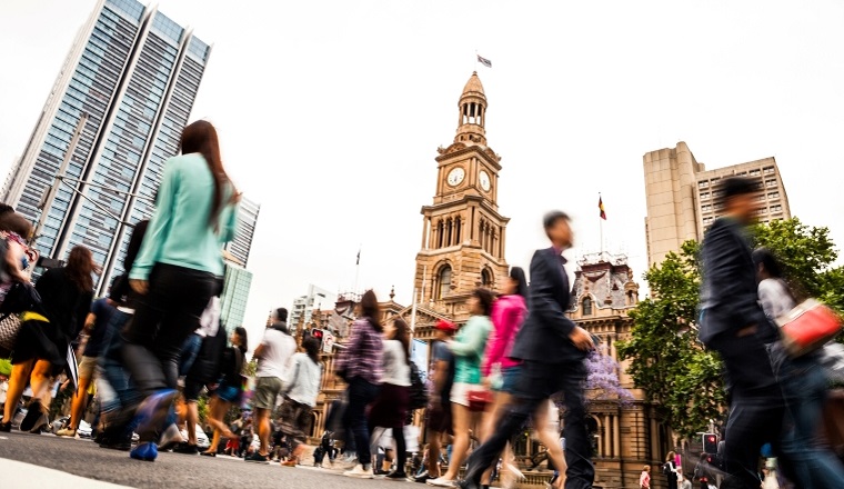Crowds crossing a road in the city at peak hour.