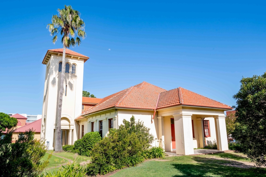 A Tuscan style clock tower and building with a palm tree next to it