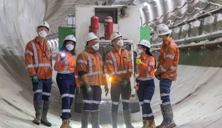 Six construction workers in safety gear standing in a tunnel