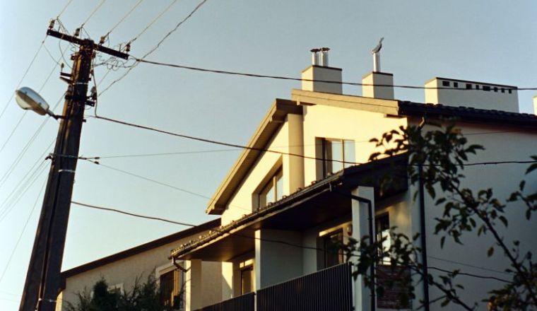 A white house with front terrace next to an electricity pole.