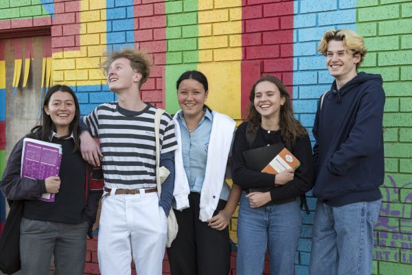 Five young people standing together and smiling. 