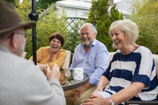 Image of 4 seniors sitting around an outside table laughing