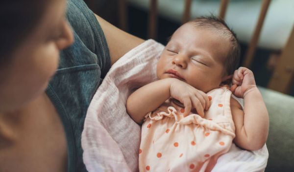a person looks down at a newborn baby in their arms
