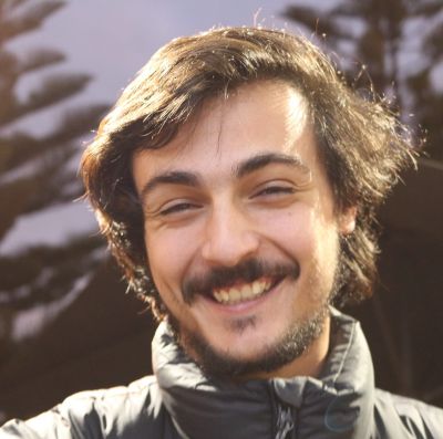 A man with brown hair and a moustache smiles at the camera.