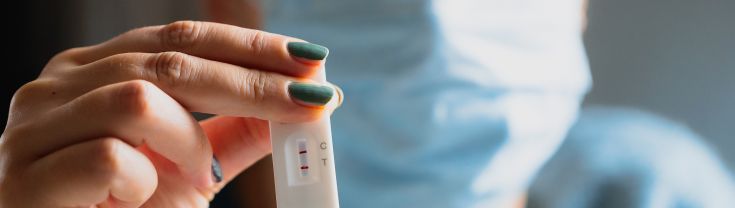 image of someone holding a positive rapid antigen test