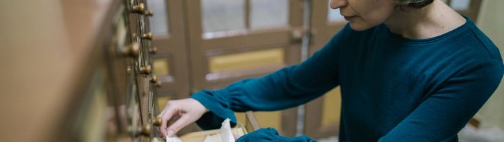 woman searches through old archive shelf for item card