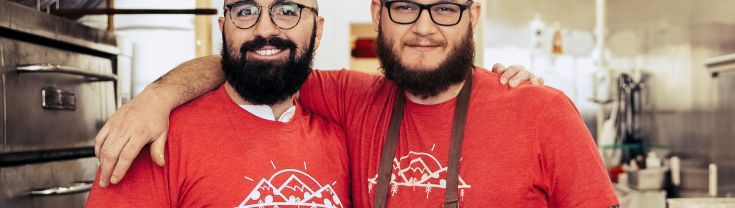 Two men wearing red shirts working at a pizza shop