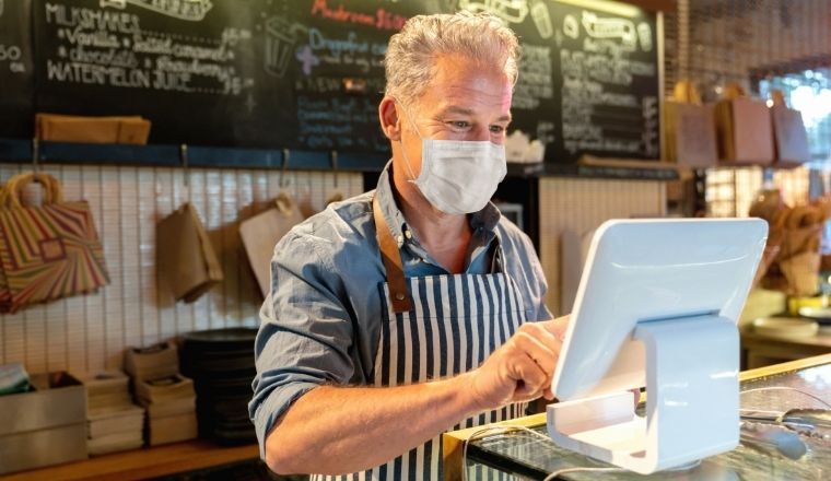 A business manager working at a cafe with a face mask on