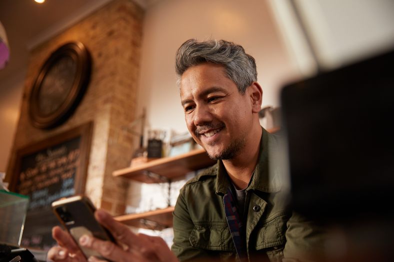 Image of male cafe worker on his mobile phone behind the counter