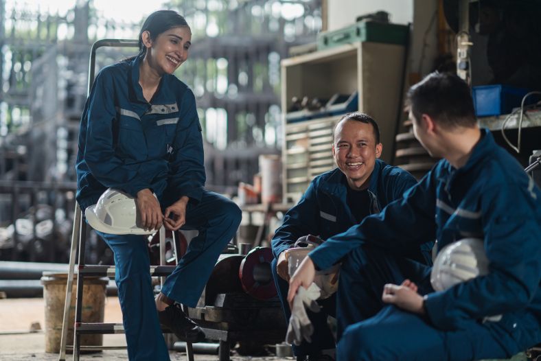 A group of three factory workers having a conversation while taking a break.