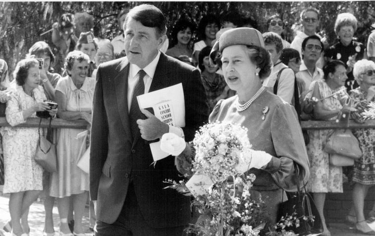 Black and white photo of The Queen with Premier Neville Wran with crowds in the background at the Sydney Entertainment Centre
