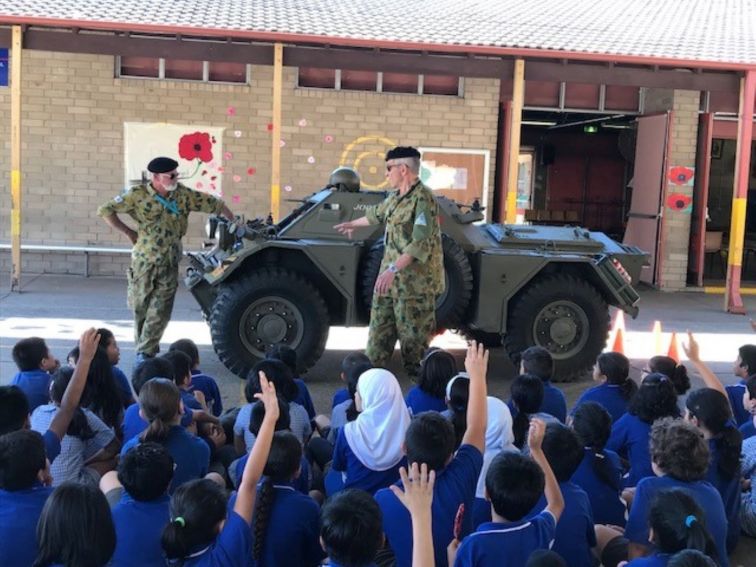 Museum volunteers show a Ferret Scout Car to young school students and answer their many questions
