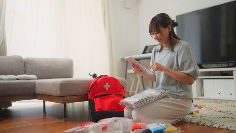 A woman packing an emergency kit on her lounge room floor